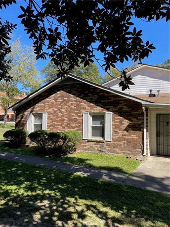 Side view of a single-story brick house with white shutters.