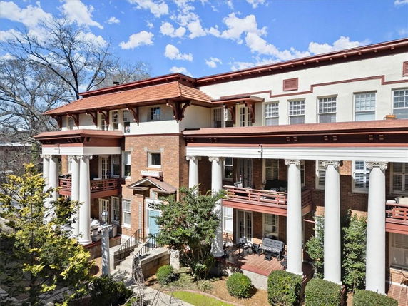 Front view of a large multi-story building with red tile roofing and white columns.