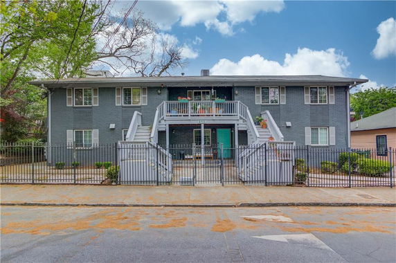 Front view of a two-story apartment building with external staircases and a gated entrance.