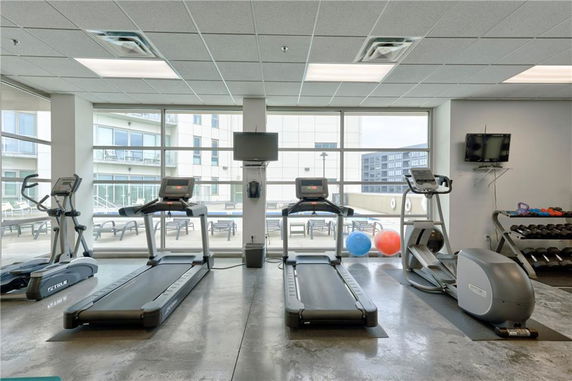 Indoor gym with treadmills, exercise bikes, and weights.