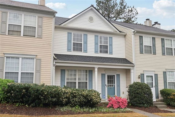 Front view of a two-story townhouse with blue shutters and white siding.
