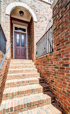 Front view of a brick house entrance with steps leading to a wooden door.