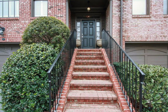 Front view of a brick house with stairs leading to the entrance.