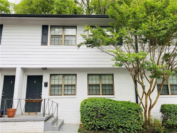 Front view of a two-story house with white siding and black doors.