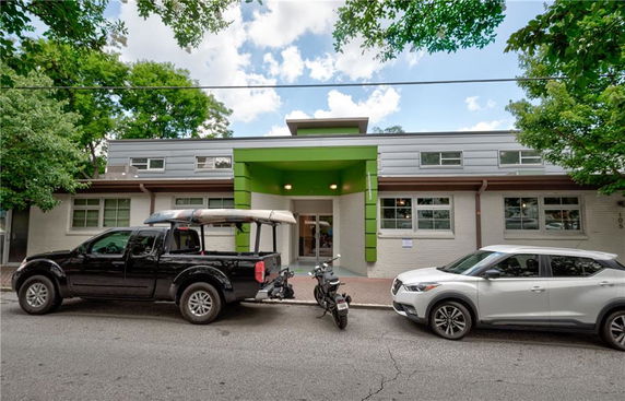 Front view of a modern building with green accents and multiple windows.