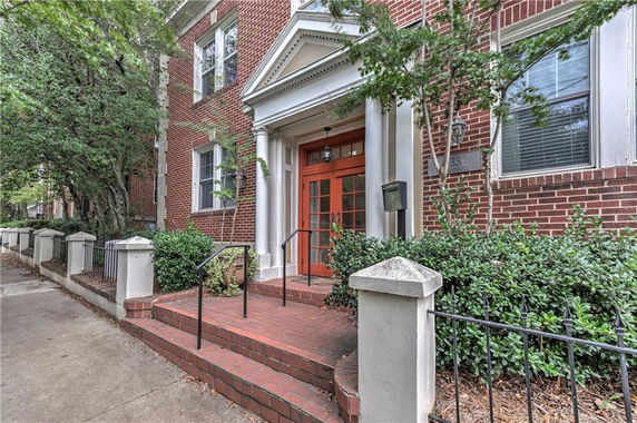 Front view of a brick building with a traditional entrance featuring columns and double doors.