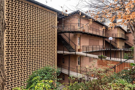 Front view of a multi-story building with external staircases and a decorative brick facade.