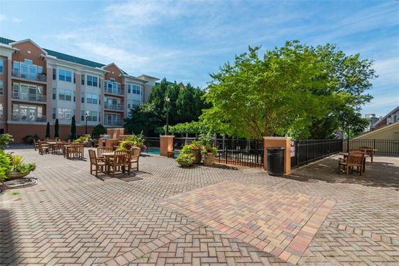 Outdoor patio area with tables and chairs next to a multi-story residential building.