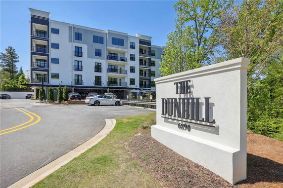 Front view of a multi-story residential building with a parking area in front.