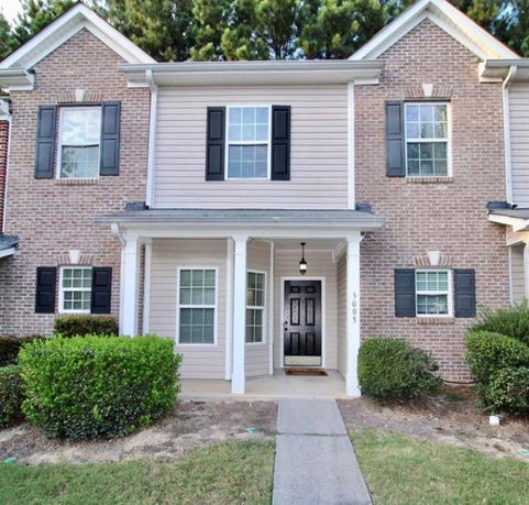 Front view of a two-story house with a covered porch and brick exterior.