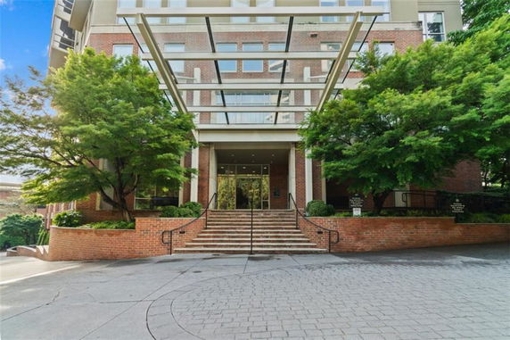 Front view of a multi-story building with glass entrance and brick facade.