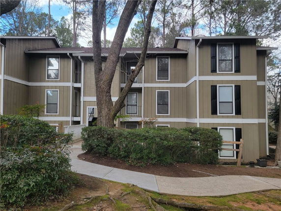 Front view of a multi-story residential building with beige siding and white trim.