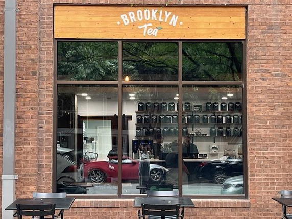 Front view of a brick building with large window displaying interior of Brooklyn Tea shop.