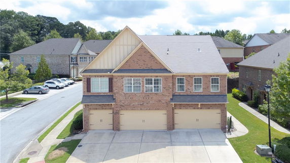 Front view of a two-story brick house with a double garage and gable roof.