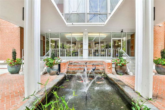 Front view of a building entrance with glass doors and windows, brick exterior, and a decorative fountain.