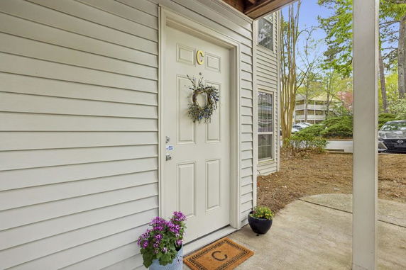 Front view of an entrance door with decorative wreath and potted plants.