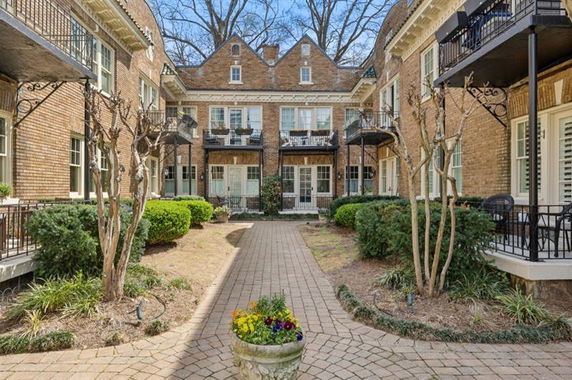 View of a multi-story brick building with balconies and a central courtyard.