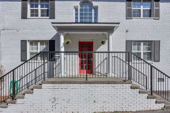 Front view of a two-story house with a red door and white brick exterior.