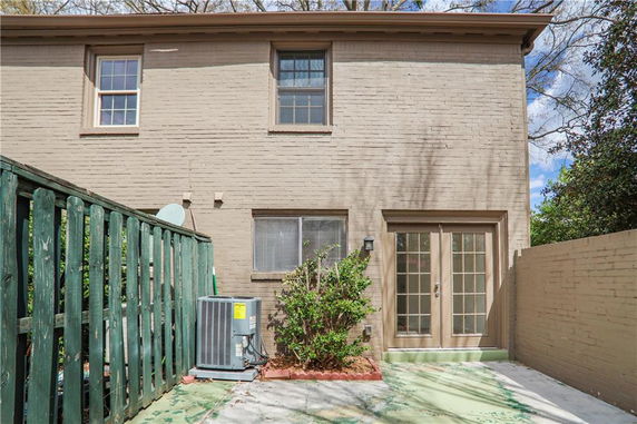 Back view of a two-story house with tan brick exterior and large glass double doors.
