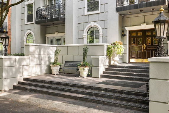 Front view of a building entrance with a staircase and decorative lamps.