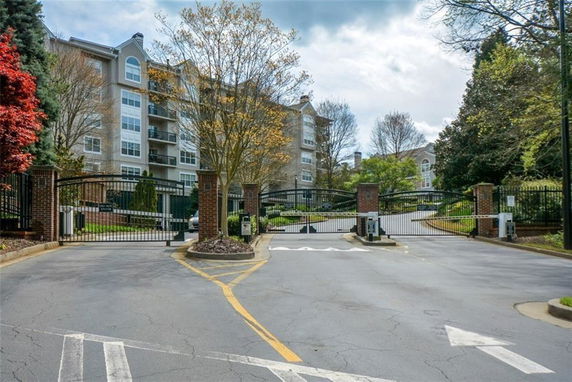 Front view of a multi-story apartment building behind a gated entrance.