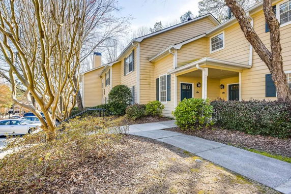Front view of a two-story house with yellow siding and a small porch.