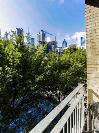 View of city skyline from a balcony with trees in the foreground.