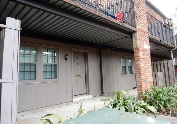 Front view of a lower level apartment unit with brick and wood exterior.