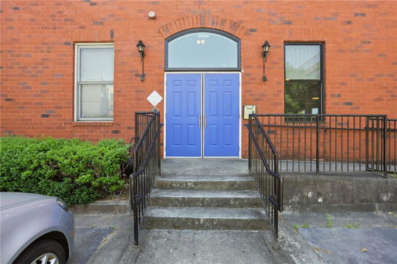 Front view of a brick building with blue double doors and a ramp leading up to the entrance.