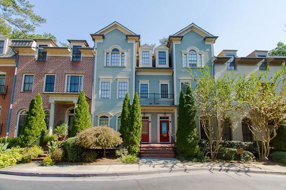 Front view of a multi-story townhouse with red doors and blue siding.