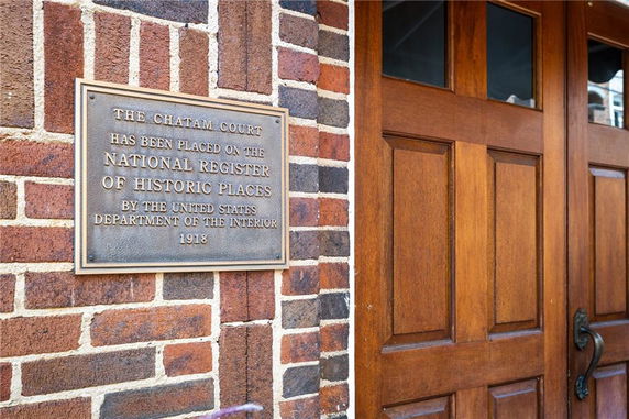 Front view of a historic building entrance with a wooden door and a plaque indicating its listing on the National Register of Historic Places.