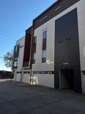 Front view of a multi-story building with modern design and garage doors.