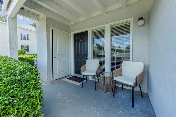 Front view of a house with a small porch featuring two chairs and a table.