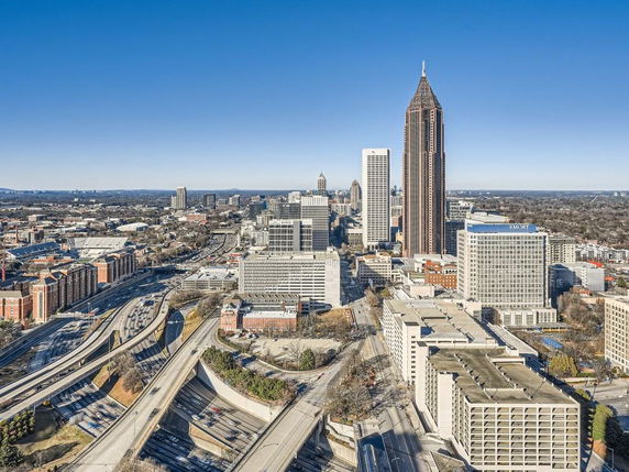 Panoramic view of a cityscape with tall buildings and highway seen from above.