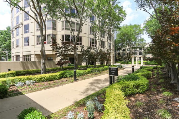 Front view of a multi-story building with large windows and landscaped gardens.