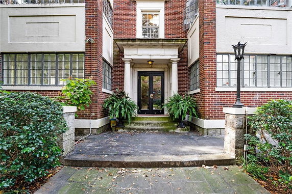 Front view of a brick building entrance with large windows and a covered doorway.