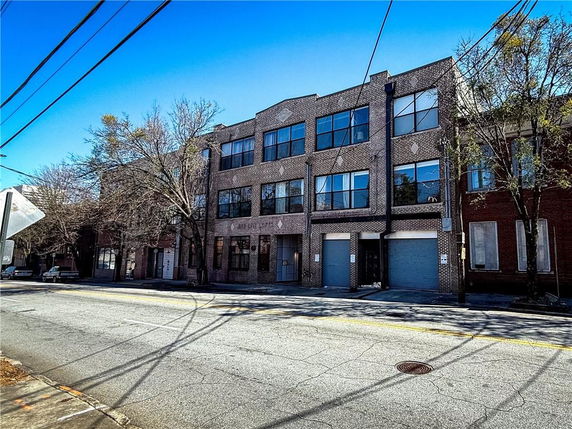 Front view of a three-story brick building with large windows and garage entrances on the ground floor.