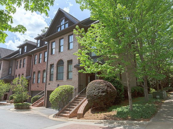 Front view of a row of multi-story brick townhouses with gabled roofs.