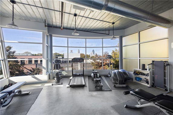 Interior view of a modern gym with large windows and fitness equipment.