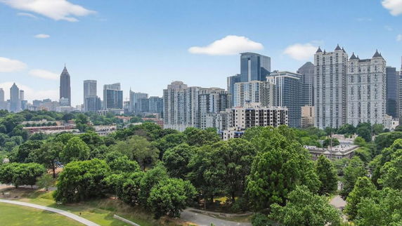 Panoramic view of city skyline with multiple tall buildings and greenery.