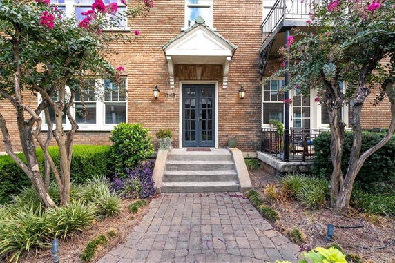 Front view of a brick house entrance with a small porch and a stairway leading up to the door.