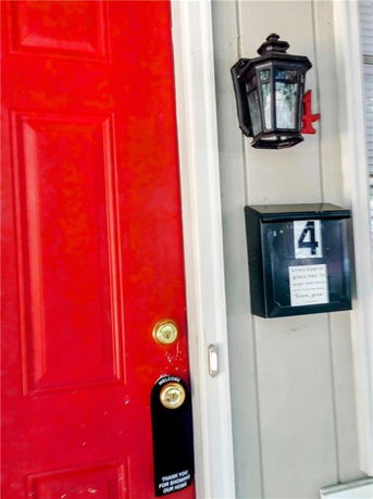 Front view of a house entrance with a red door and a wall-mounted lantern.