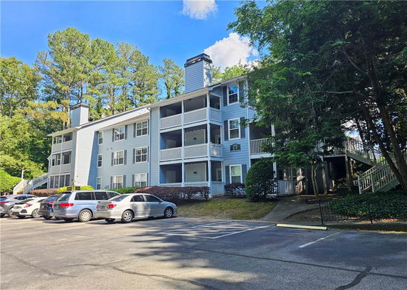 Front view of a three-story apartment building with multiple balconies and chimneys.
