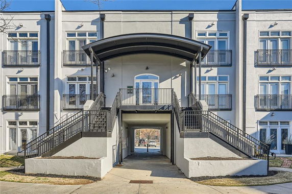 Front view of a multi-story building with balconies and a central archway.
