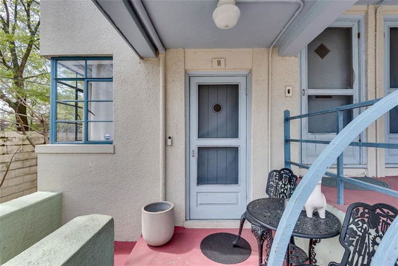 Front view of a house entrance with a small patio area and metal furniture.