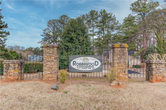 Entrance view of Robinwood Condominiums with stone pillars and metal gate.