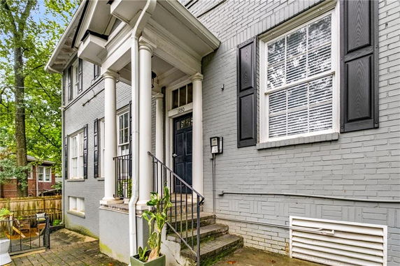 Front view of a two-story house with a columned porch and black shutters.