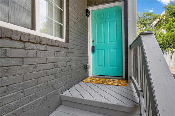 Front view of a house door with turquoise color and gray brick exterior.