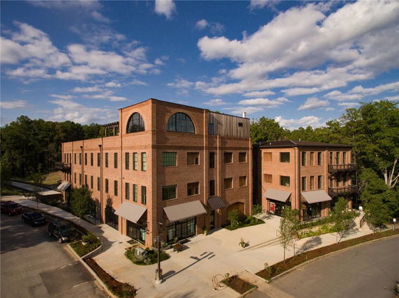 Front view of a multi-story brick building with large arched windows on the top floor.