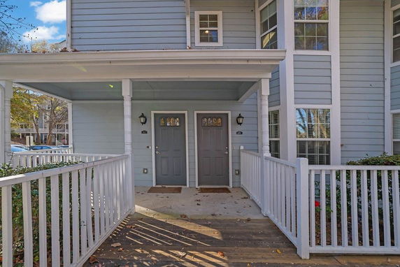 Front view of a multi-story building with two doors and a porch with railing.